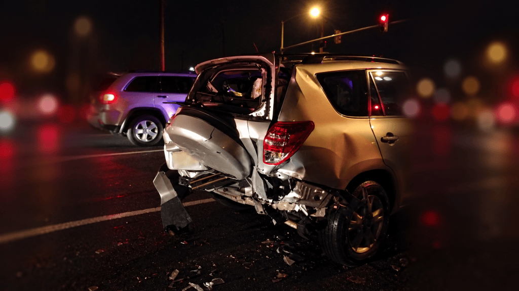 Silver Toyota RAV4 with severe rear-end damage after a nighttime collision.